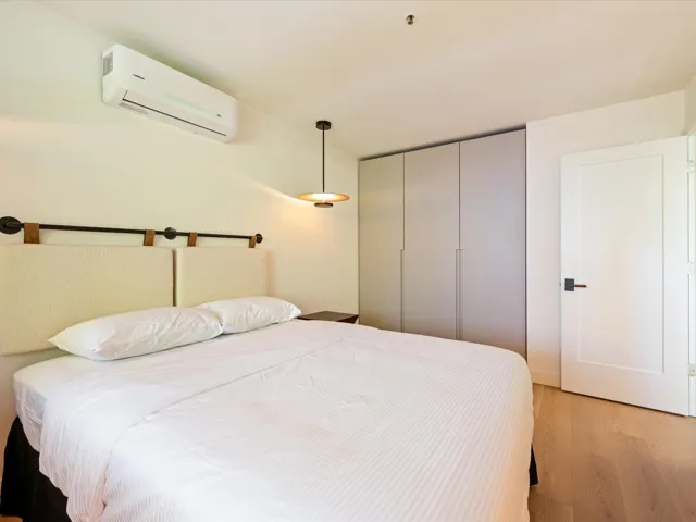 Primary bedroom with light wood-style flooring and a wall mounted AC