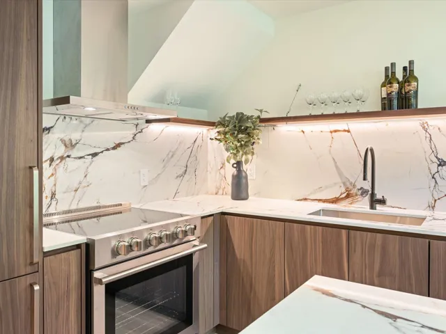 Kitchen with tasteful backsplash, electric range, wall chimney range hood, brown cabinetry, and modern cabinets