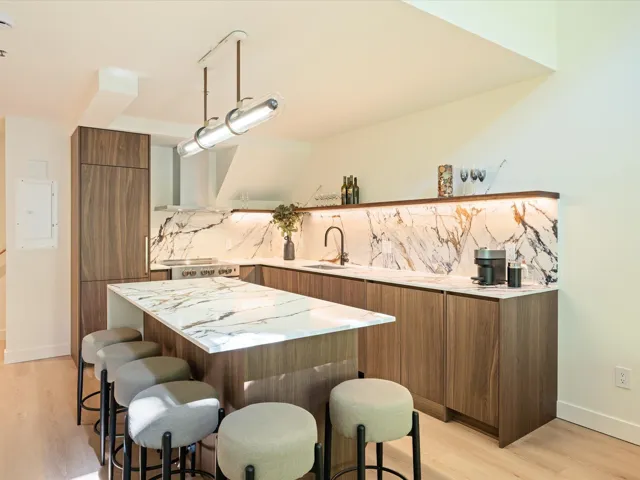 Kitchen with modern cabinets, brown cabinetry, a kitchen breakfast bar, backsplash, and light wood-style floors