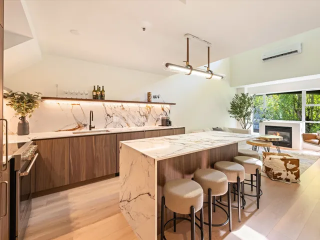 Kitchen featuring a kitchen breakfast bar, brown cabinetry, light stone countertops, modern cabinets, and light wood finished floors