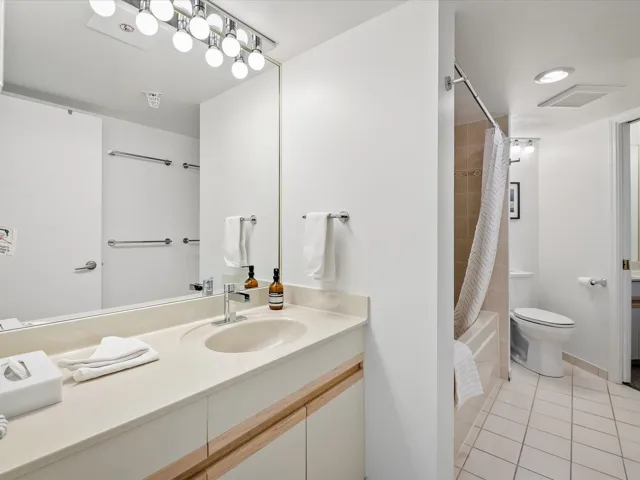 Bathroom with light tile patterned floors, vanity, and shower / tub combo with curtain
