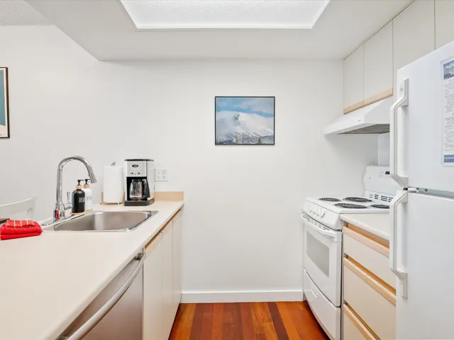 Kitchen with white cabinetry, white appliances, light countertops, dark wood finished floors, and under cabinet range hood