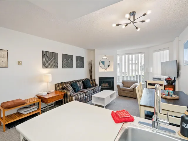 Carpeted living area featuring a chandelier, a textured ceiling, and a glass covered fireplace