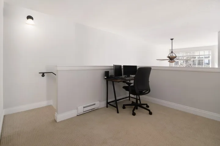 Carpeted office with a baseboard heating unit, baseboards, and a ceiling fan