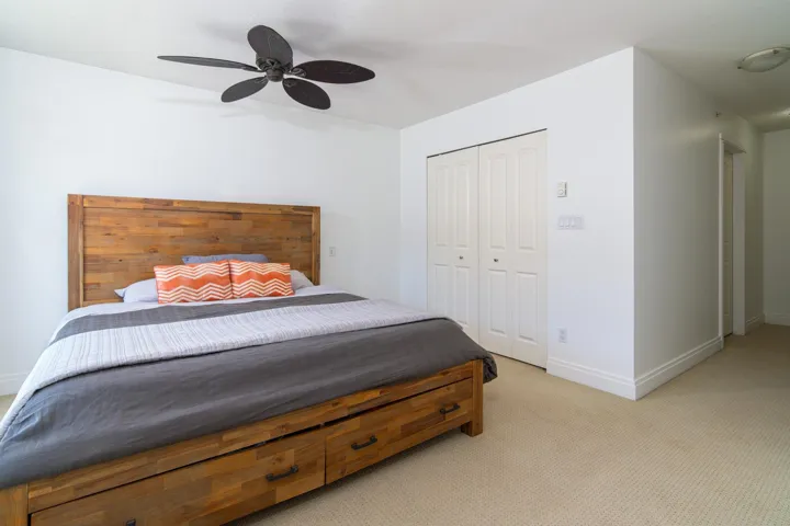 Bedroom featuring light carpet, a closet, a ceiling fan, and baseboards