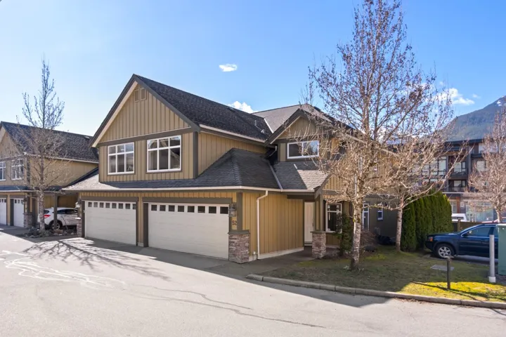 View of front of house featuring driveway, stone siding, board and batten siding, roof with shingles, and an attached garage