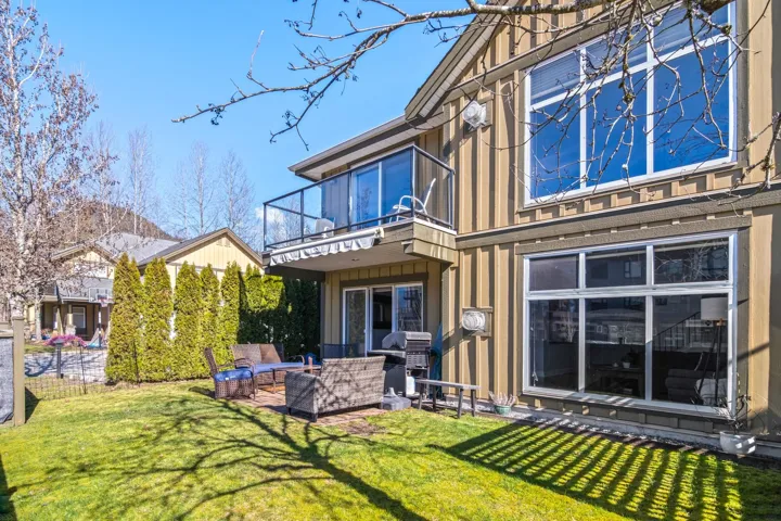 Rear view of house featuring a balcony, a lawn, board and batten siding, and an outdoor hangout area