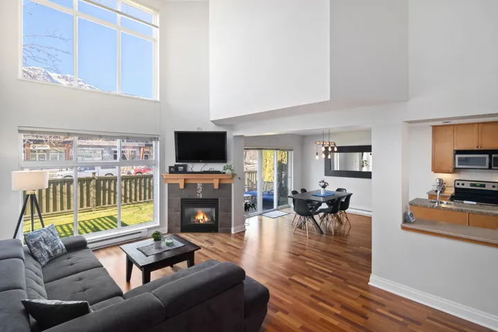 Living room featuring a towering ceiling, baseboards, dark wood-style floors, and a tiled fireplace