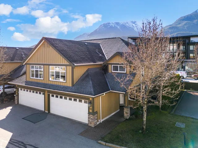 View of front of home with board and batten siding, stone siding, a mountain view, and driveway