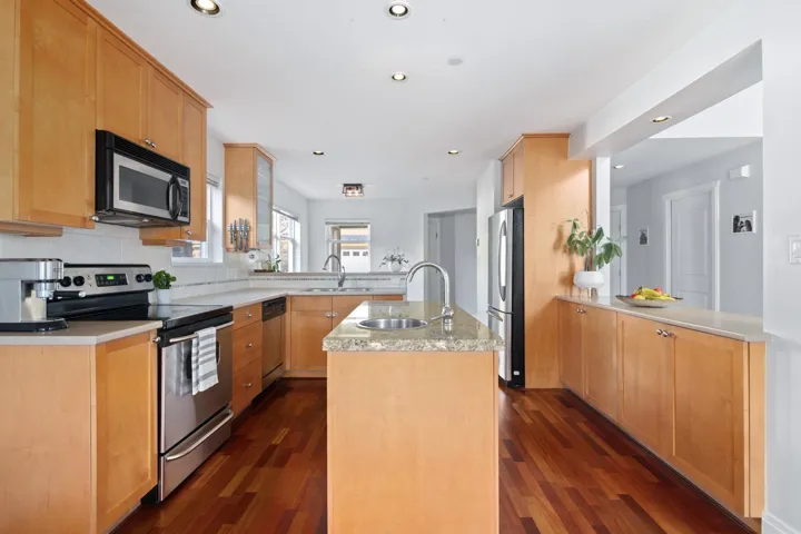 Kitchen with a sink, stainless steel appliances, a peninsula, and a kitchen island with sink