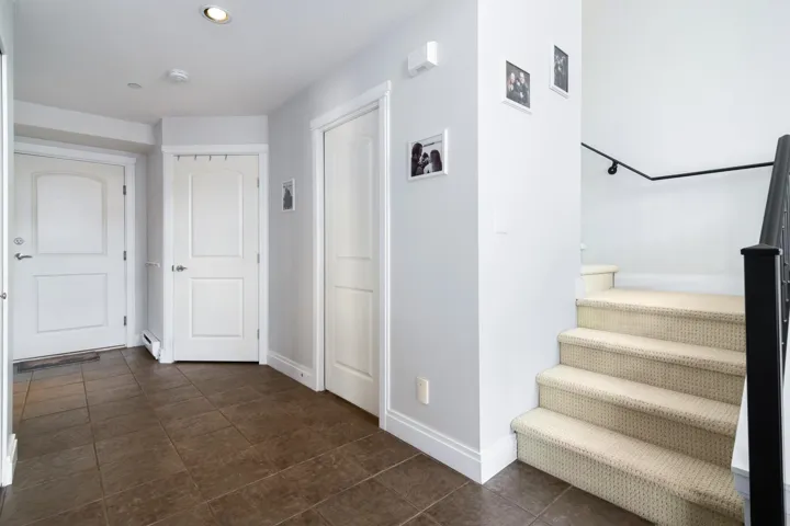 Hallway with stairs, dark tile patterned flooring, and baseboards