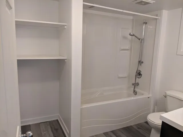 Full bathroom featuring vanity, toilet, baseboards, visible vents, and wood finished floors
