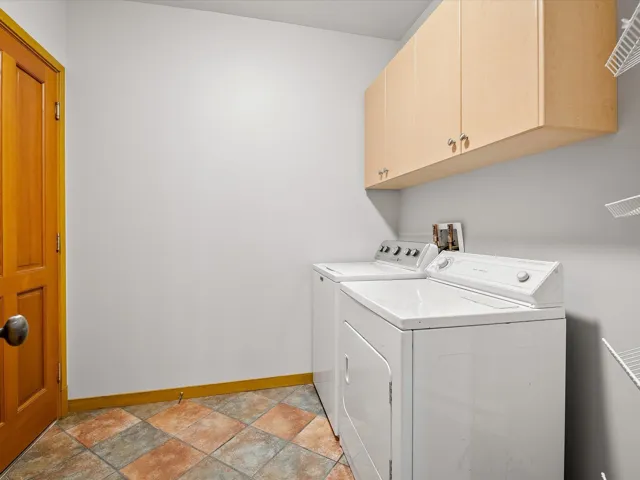Laundry area featuring stone tile flooring, independent washer and dryer, and cabinet space