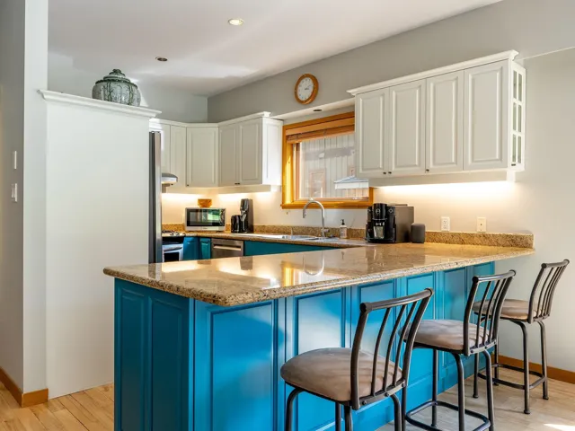Kitchen featuring blue cabinets, light stone counters, a breakfast bar, light wood-type flooring, and recessed lighting