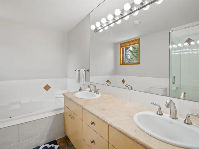 Full bathroom featuring double vanity, a garden tub, and a shower stall