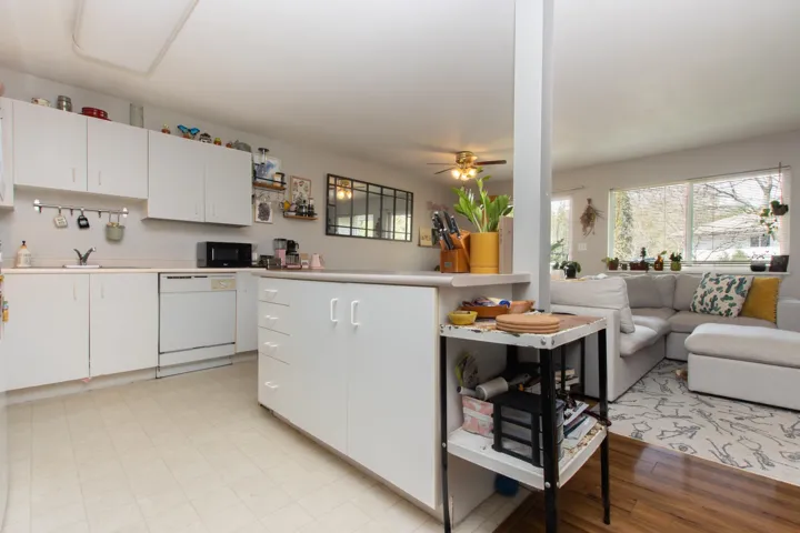 Kitchen with white cabinets, a sink, open floor plan, white dishwasher, and light countertops