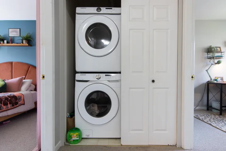 Washroom with stacked washer and clothes dryer, carpet flooring, baseboards, and laundry area