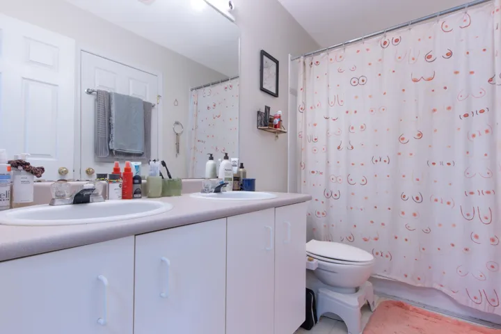 Bathroom with double vanity, tile patterned floors, toilet, and a sink