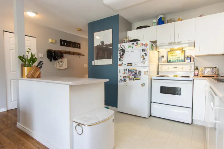 Kitchen with white cabinets, under cabinet range hood, white appliances, and light countertops