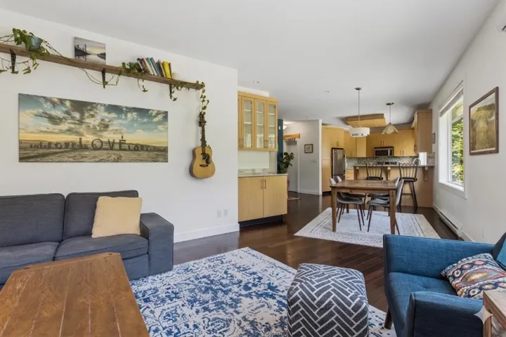 Open-concept living space with dark wood-finish flooring, white walls, and recessed lighting
