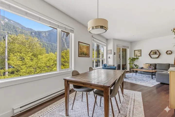 Dining area with expansive windows showcasing a mountain backdrop and lush trees