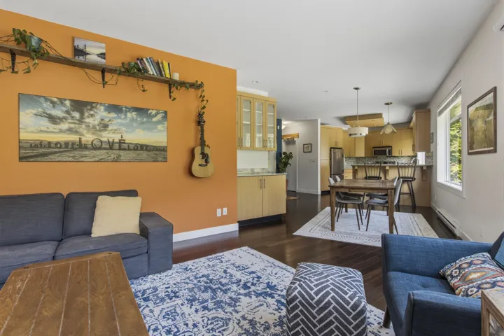 Open-concept living space featuring wood-finish flooring, a dining area, and a kitchen with light wood-finish cabinetry