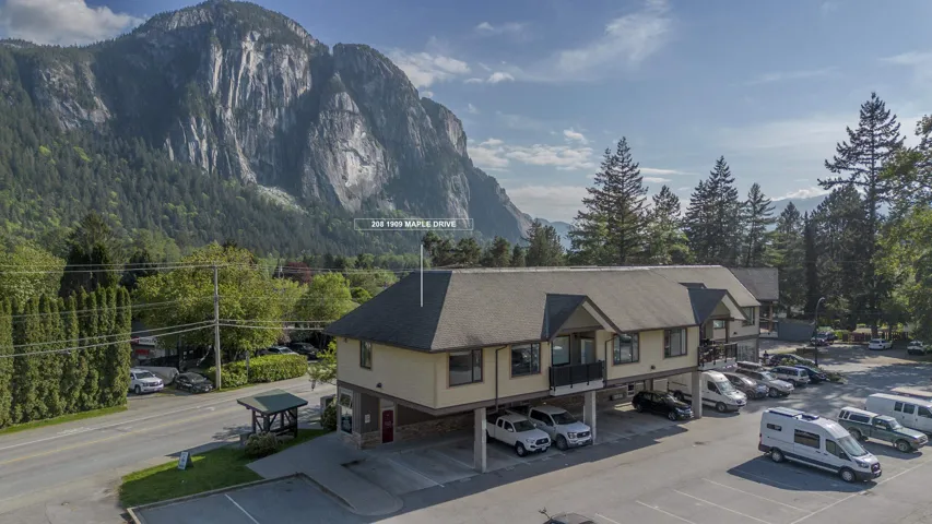 Two-story commercial building with multiple balconies, a pitched roof, and ample surface parking