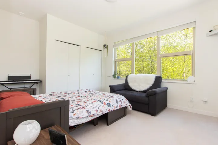 Carpeted bedroom featuring two closets, baseboards, and multiple windows