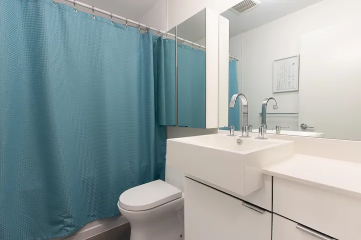 Bathroom featuring visible vents, toilet, vanity, and shower / tub combo