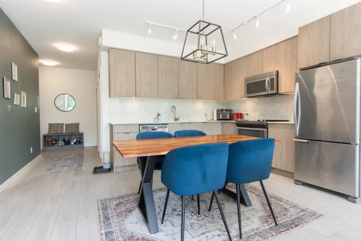 Kitchen featuring stainless steel appliances, track lighting, modern cabinets, decorative backsplash, and a chandelier