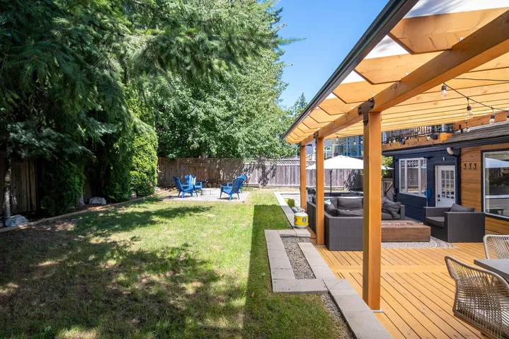 Fenced backyard with a wooden deck and an outdoor living space with a fire pit