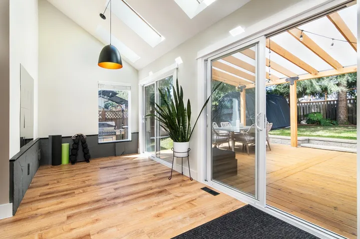 Doorway featuring a skylight, wood finished floors, and high vaulted ceiling