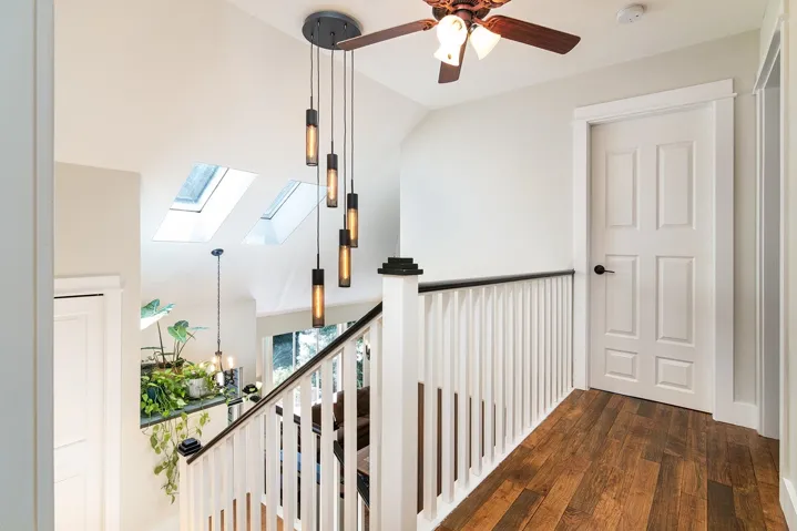 Hallway with an upstairs landing, a skylight, and dark wood-type flooring