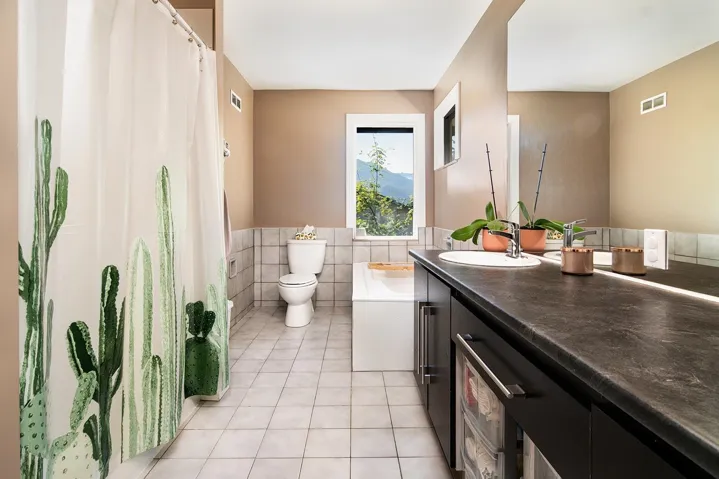 Full bath with tile patterned floors, tile walls, vanity, a tub to relax in, and wainscoting