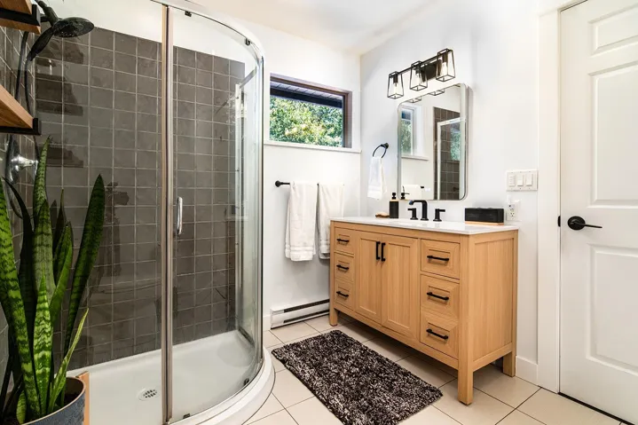 Bathroom featuring a shower stall, vanity, baseboard heating, and tile patterned flooring