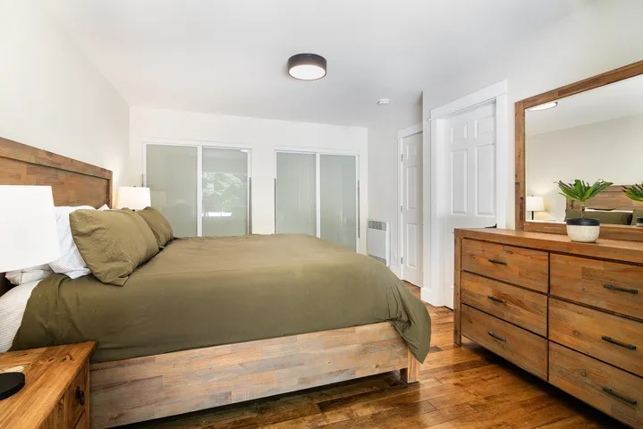 Bedroom with dark wood-style flooring, multiple closets, and radiator heating unit