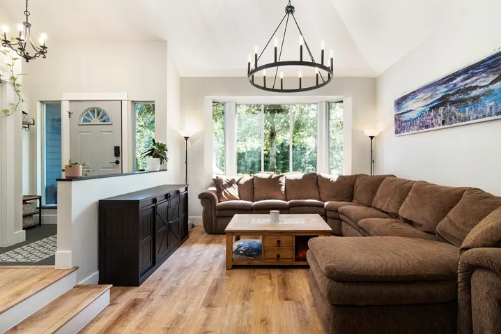 Living area featuring a chandelier, light wood-style flooring, and vaulted ceiling