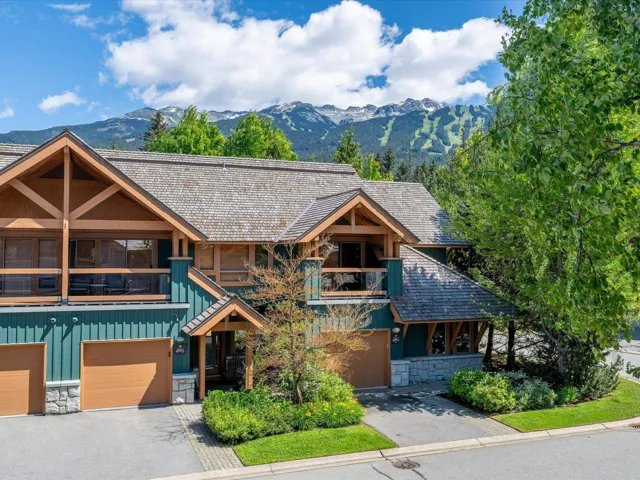 Rustic home featuring stone siding, a balcony, board and batten siding, a mountain view, and asphalt driveway