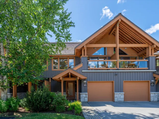 View of front of property with a balcony, stone siding, asphalt driveway, and a garage