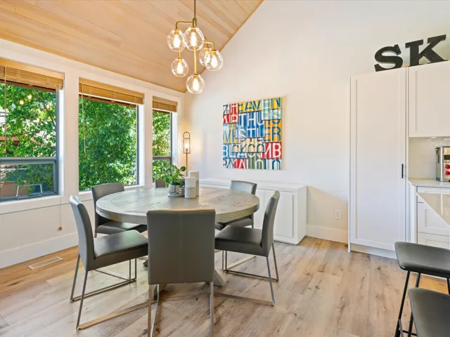 Dining room with wood ceiling, light wood-style flooring, a chandelier, and high vaulted ceiling
