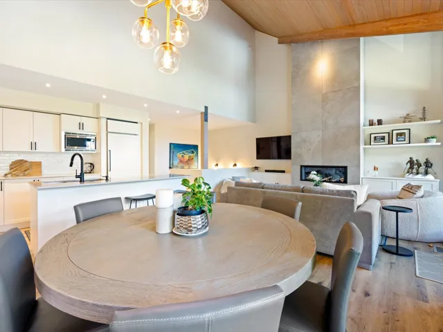 Dining area with light wood finished floors, a tile fireplace, a high ceiling, a wood ceiling with exposed beams, and recessed lighting