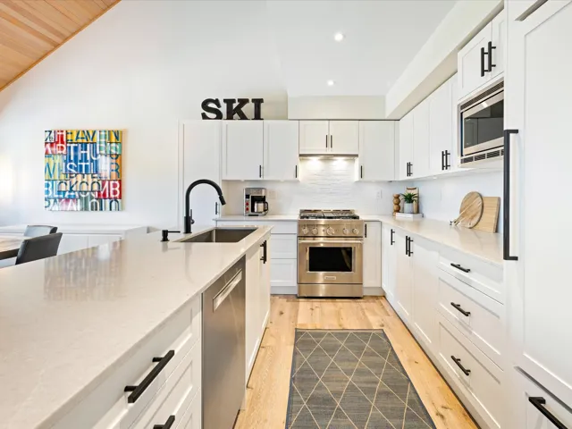 Kitchen with appliances with stainless steel finishes, light wood-type flooring, recessed lighting, backsplash, and white cabinets
