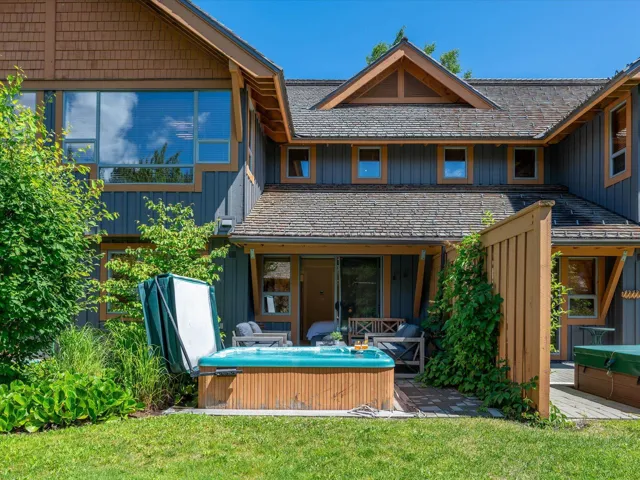 Rear view of property featuring a hot tub, a yard, and board and batten siding