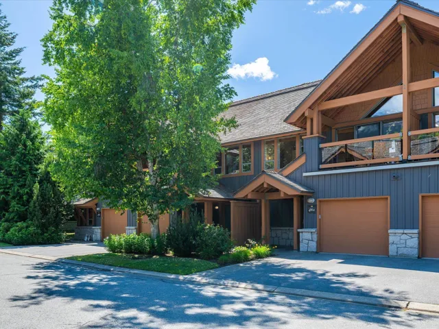 View of front of home with a balcony, stone siding, driveway, and a garage