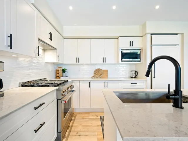 Kitchen featuring stainless steel appliances, recessed lighting, light stone counters, white cabinetry, and tasteful backsplash