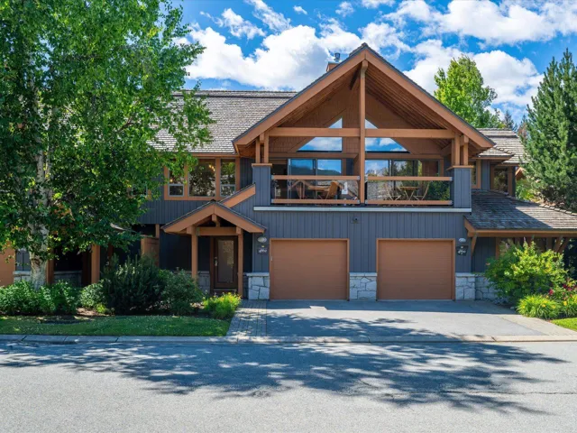 View of front of house featuring stone siding, a balcony, driveway, and a garage