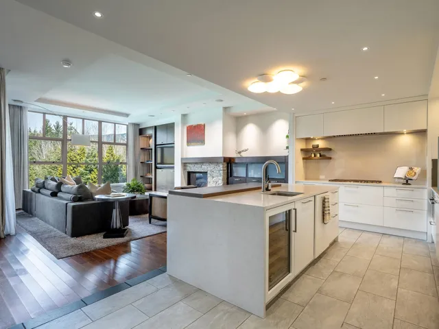 Kitchen featuring modern cabinets, open floor plan, white cabinets, an island with sink, and tasteful backsplash