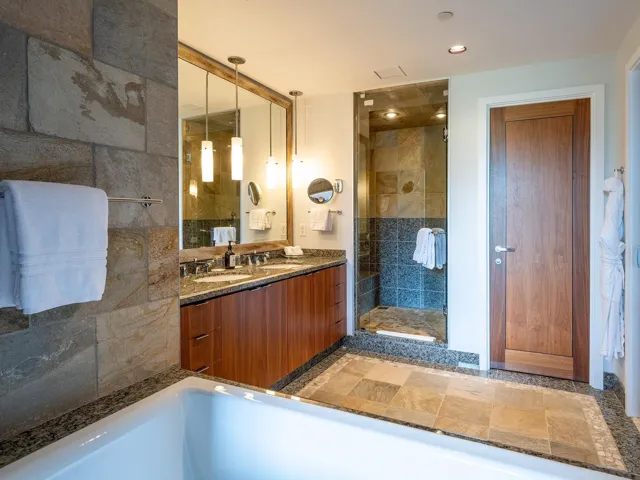 Bathroom featuring a shower stall, double vanity, a bathtub, light stone finish floors, and recessed lighting