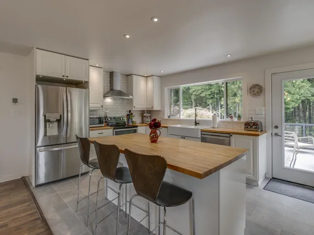 Kitchen featuring stainless steel appliances, wall chimney exhaust hood, butcher block counters, tasteful backsplash, and recessed lighting
