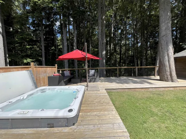 Deck featuring a covered hot tub and a lawn